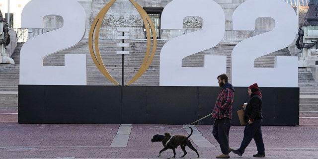 Patrons walk past the College Football Playoff National Championship display on Monument Circle, viernes, ene. 7, 2022, in Indianapolis. Alabama and Georgia are scheduled to play in the championship game on Jan. 10 at Lucas Oil Stadium.