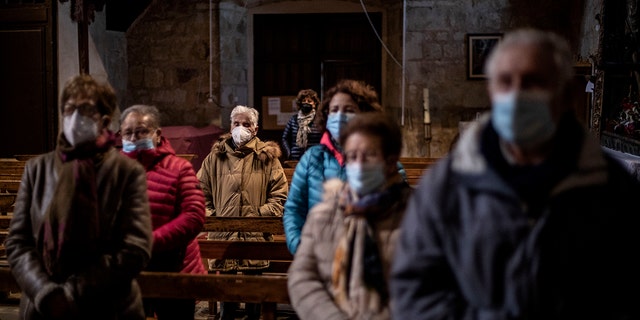 Parishioners stand while praying at the Saturday Mass the Catholic church of Cazurra, Spain