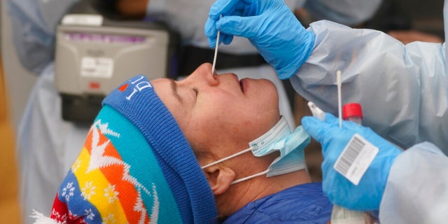 A member of the Salt Lake County Health Department COVID-19 testing staff performs a test on Chrissy Nichols outside the Salt Lake County Health Department Tuesday, Jan. 4, 2022, in Salt Lake City. (AP Photo/Rick Bowmer) 