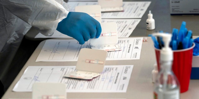 Nurse Ray Akindele processes COVID-19 rapid antigen tests at a testing site in Long Beach, California, Thursday, Jan. 6, 2022. (AP Photo/Jae C. Hong)