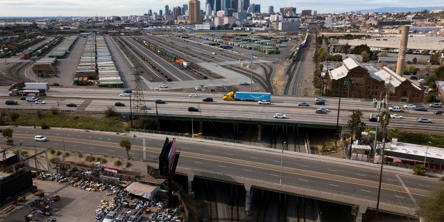 An aerial image from Jan. 16, 2022 shows the Los Angeles skyline as a semi-truck carrying an Amazon Prime trailer crosses a bridge over a section of Union Pacific train tracks.