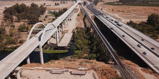 In this aerial image taken on Aug. 26, 2021, vehicles drive past farmland and part of the California High Speed Rail Authority San Joaquin River viaduct construction project alongside U.S. Highway 99 through the Central Valley between Madera County and Fresno County, California.
