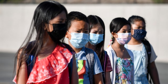 Masked students wait to be taken to their classrooms at Enrique S. Camarena Elementary School July 21, 2021, in Chula Vista, Calif. 