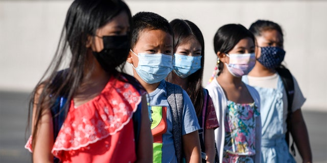 Masked students wait to be led into a classroom at Enrique S. Camarena Elementary School in Chula Vista, California, July 21, 2021. 