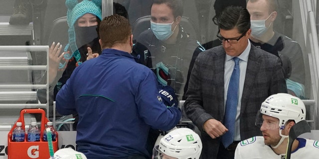 Seattle Kraken fan Nadia Popovici, upper left, gestures toward Vancouver Canucks assistant equipment manager Brian "红色的" 汉密尔顿, 从左数第二, after they were introduced during the first period of an NHL hockey game, 星期六, 一月. 1, 2022, 在西雅图.