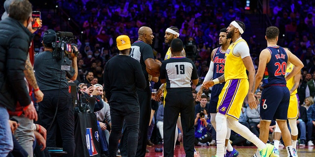 Los Angeles Lakers' Carmelo Anthony, top center, is held back by officials after having a word with a fan in the stands during the second half of an NBA basketball game against the Philadelphia 76ers, Thursday, Jan. 27, 2022, in Philadelphia.