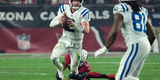 Indianapolis Colts quarterback Carson Wentz (2) is tripped up by Arizona Cardinals safety Budda Baker (3) during the second half of an NFL football game, Saturday, Dec. 25, 2021, in Glendale, Ariz.
