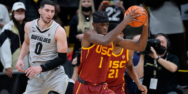 Southern California forward Chevez Goodwin, voor, pulls in a loose ball as Colorado guard Luke O'Brien watches during the first half of an NCAA college basketball game Thursday, Jan.. 20, 2022, in Boulder, Colo. 