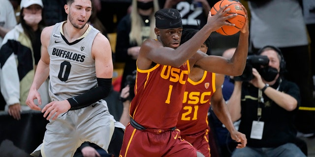 Southern California forward Chevez Goodwin, front, pulls in a loose ball as Colorado guard Luke O'Brien watches during the first half of an NCAA college basketball game Thursday, Jan. 20, 2022, in Boulder, Colo.