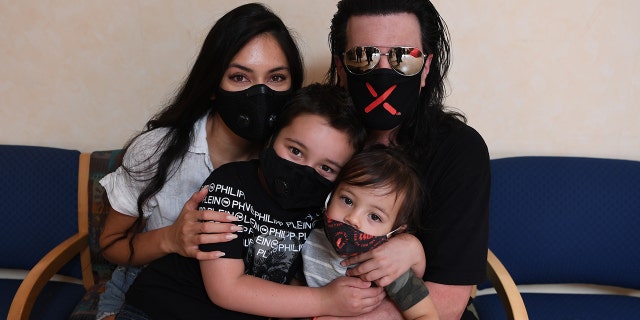 Criss Angel, 对, is pictured with his wife Shaunyl Benson and sons Johnny Crisstopher Sarantakos, 中央, and Xristos Yanni Sarantakos. The illusionist announced in an emotional post that Johnny's cancer is in remission.