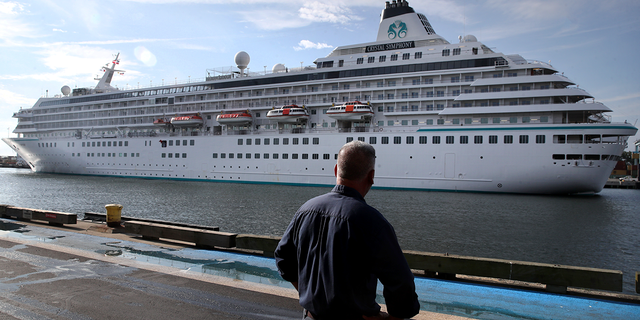 A pedestrian watches as the Crystal Symphony cruise ship arrives at Flynn Cruiseport in Boston, Massachusetts, on Aug. 18, 2021.