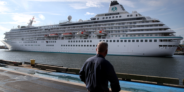 A pedestrian watches as the Crystal Symphony cruise ship arrives at Flynn Cruiseport in Boston, Massachusetts, on Aug. 18, 2021.