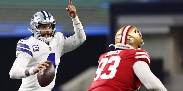 Dallas Cowboys' Dak Prescott, left, looks to pass against the San Francisco 49ers during the second half of an NFC Wild Card playoff game at AT and T Stadium on January 16, 2022 in Arlington, Texas.