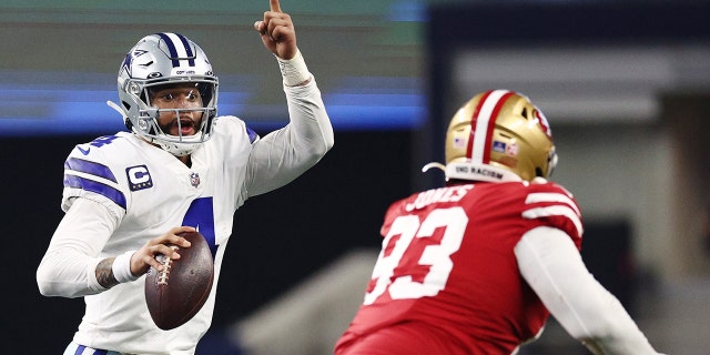 Dak Prescott, de los Dallas Cowboys, a la izquierda, busca un pase contra los San Francisco 49ers durante la segunda mitad de un partido de playoffs de comodines de la NFC en el AT and T Stadium el 16 de enero de 2022 en Arlington, Texas.