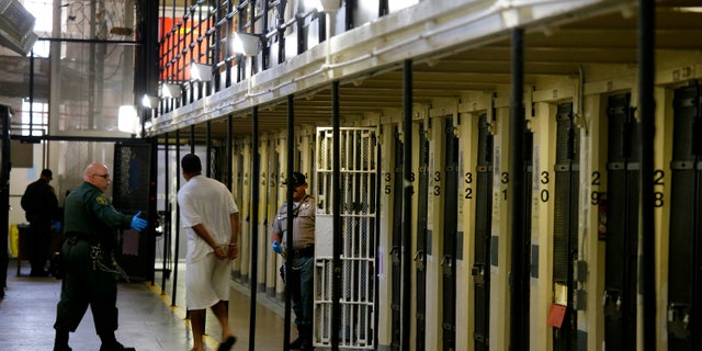 In this Aug. 16, 2016, file photo a condemned inmate is led out of his east block cell on death row at San Quentin State Prison, in San Quentin, Calif. Two inmates at other California correctional facilities died after being attacked this week, prison officials said