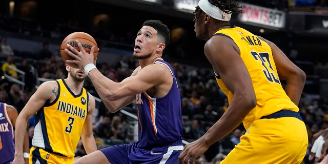 Phoenix Suns' Devin Booker goes to the basket against Indiana Pacers' Myles Turner (33) during the second half of an NBA basketball game, Friday, Jan. 14, 2022, in Indianapolis.