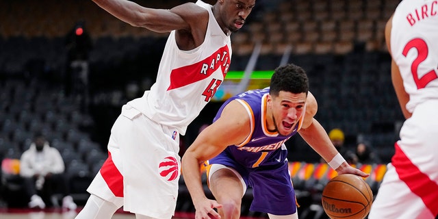 Phoenix Suns guard Devin Booker (1) drives past Toronto Raptors forward Pascal Siakam (43) during the first half in Toronto Jan. 11, 2022.