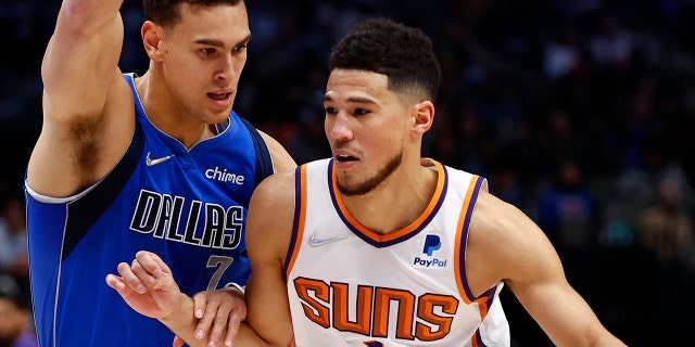 Phoenix Suns guard Devin Booker (1) drives against Dallas Mavericks forward Dwight Powell (7) during the first half of an NBA basketball game Thursday, Jan. 20, 2022, a Dallas.