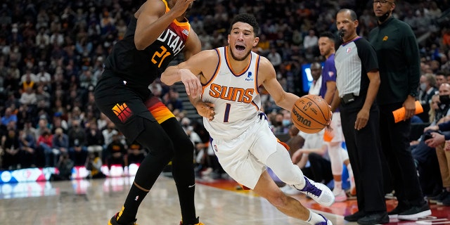 Phoenix Suns guard Devin Booker (1) drives around Utah Jazz center Hassan Whiteside (21) in the second half during an NBA basketball game Wednesday, Jan. 26, 2022, in Salt Lake City.