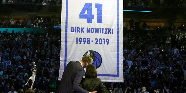 Former Dallas Mavericks Dirk Nowitzki, sinistra, and his wife Jessica Olsson watch a banner being raised during a number retirement ceremony for Nowitzki after an NBA basketball game between the Golden State Warriors and Dallas Mavericks in Dallas, mercoledì, Jan. 5, 2022.