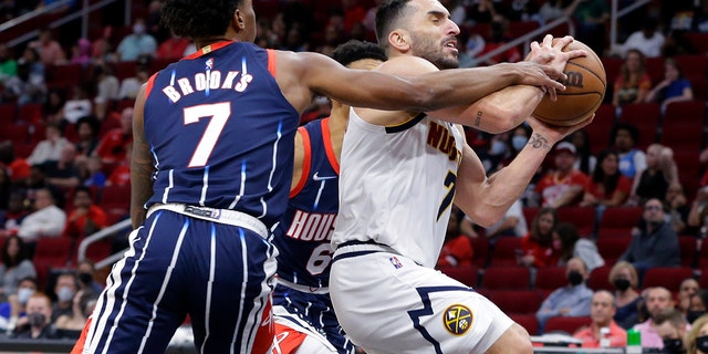 Houston Rockets guard Armoni Brooks, left, fouls Denver Nuggets guard Facundo Campazzo during the first half of an NBA basketball game Saturday, Jan. 1, 2022, in Houston.