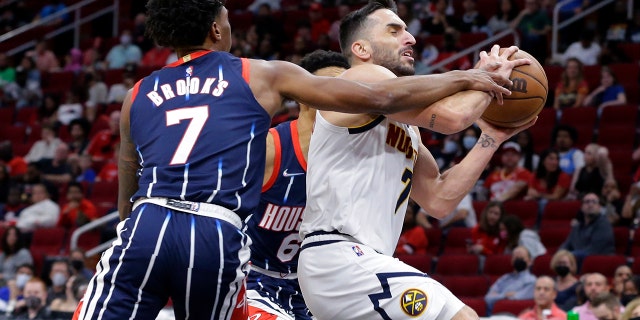 Houston Rockets guard Armoni Brooks, left, fouls Denver Nuggets guard Facundo Campazzo during the first half of an NBA basketball game Saturday, Jan. 1, 2022, in Houston.