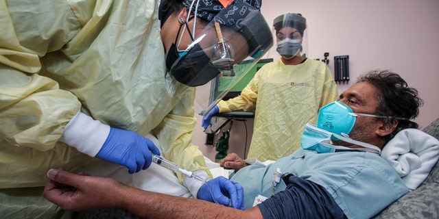 Nurse Salina Padilla, left, prepares Dr. Prabakar Tummala for Bamlanivimab, monoclonal antibody infusion at Desert Valley Hospital on Thursday, Dec. 17, 2020 in Victorville, California.