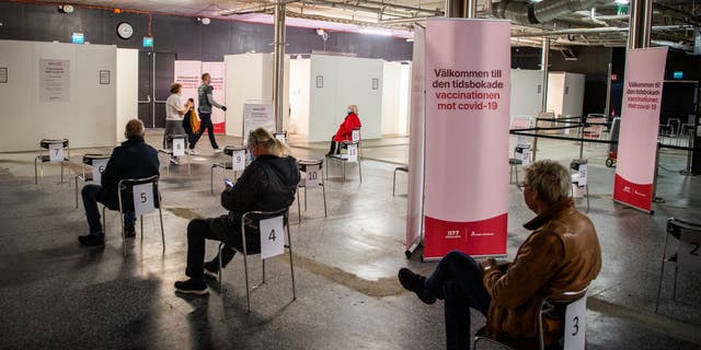 People wait to get their vaccines against COVID-19 in a nightclub turned vaccination center in Stockholm, Sweden, on April 16, 2021.
