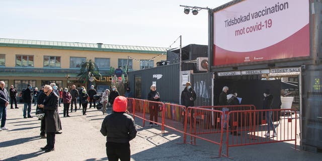 People wait in line to get their vaccines against COVID-19 outside a nightclub turned mass vaccination center in Stockholm, Sweden, on April 16, 2021.