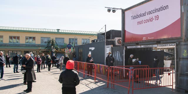 People wait in line to get their vaccines against COVID-19 outside a nightclub turned mass vaccination center in Stockholm, Sweden, on April 16, 2021.