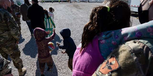 Nov 4., 2021 Children play with a ball as they walk with a group of media and military service members in an Afghan refugee camp in Holloman Air Force Base, New Mexico. (Photo by Jon Cherry/Getty Images)