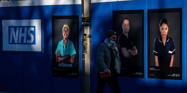 A pedestrian passes portraits of National Health Service (NHS) workers on hoardings outside a temporary structure on Friday, Jan. 7, 2022. (Chris J. Ratcliffe/Bloomberg via Getty Images)
