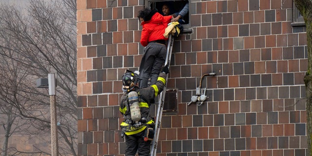 Firefighters hoisted a ladder to rescue people through their windows after a fire broke out inside a third-floor duplex apartment at 333 E. 181st St. in the Bronx Sunday. (Theodore Parisienne/New York Daily News/Tribune News Service via Getty Images)