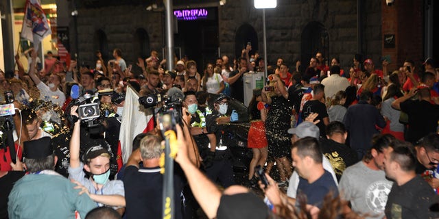 De politie gebruikt pepperspray om aanhangers van de Servische Novak Djokovic buiten de kantoren van zijn juridische team te verspreiden terwijl een auto het gebouw in Melbourne op 10 januari 2022 verlaat. 