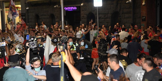 Police use pepper spray to disperse supporters of Serbia's Novak Djokovic outside the offices of his legal team as a car leaves the building in Melbourne on Jan. 10, 2022.