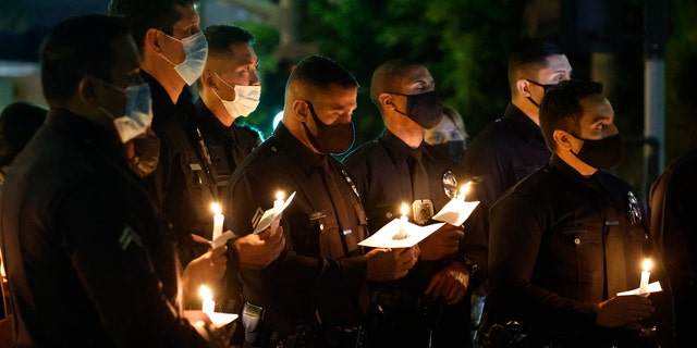 Los Angeles Police officers attend a candlelight vigil for fallen Officer Fernando Arroyos, who was shot and killed during an armed robbery attempt outside the Olympic Community Police Station Jan. 12, 2022, in Los Angeles.