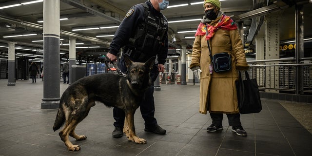 A commuter talks to a police officer with a dog on Jan. 18, 2022, at the Times Square subway station where Michelle Go was killed after being pushed onto subway tracks on Jan. 15.