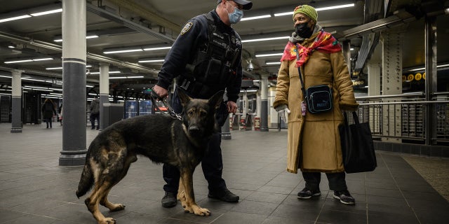 A commuter talks to a police officer with a dog on Jan. 18, 2022, at the Times Square subway station where Michelle Go was killed after being pushed onto subway tracks on Jan. 15.