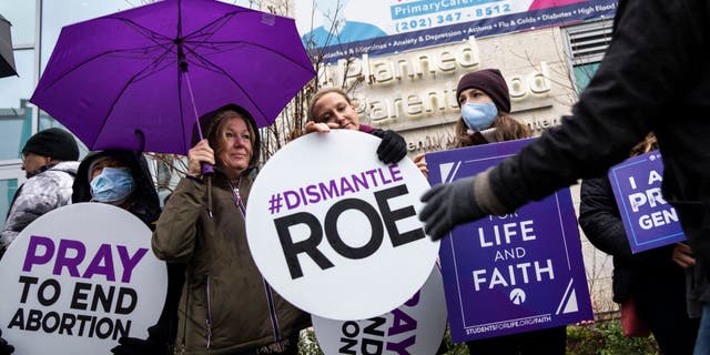 Pro-life activists pass out signs during a protest outside of a Planned Parenthood clinic on Jan. 20, 2022 in Washington, D.C. The protest was organized by the Purple Sash Revolution and Priests for Life, calling for the defunding and replacing of Planned Parenthood. 