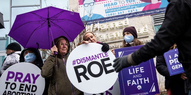 Pro-life activists pass out signs during a protest outside a Planned Parenthood clinic on Jan. 20, 2022, in Washington, D.C.