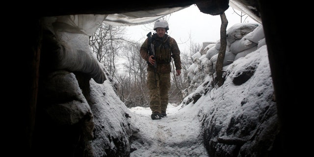 Militar de las Fuerzas Militares de Ucrania camina a lo largo de una trinchera cubierta de nieve en la región oriental de Lugansk, el 21 de enero de 2022. -