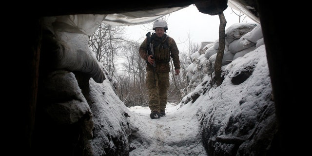 Ukrainian Military Forces serviceman walks along a snow covered trench in the eastern Lugansk region, on January 21, 2022. -