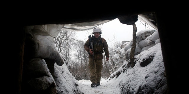 Militar de las Fuerzas Militares de Ucrania camina a lo largo de una trinchera cubierta de nieve en la región oriental de Lugansk, el 21 de enero de 2022. -