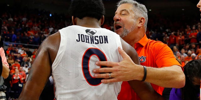 AUBURN, AL - JANUARY 22: Head Coach Bruce Pearl hugs KD Johnson #0 of the Auburn Tigers after their 80-71 win over the Kentucky Wildcats at Auburn Arena on January 22, 2022 in Auburn, Alabama.