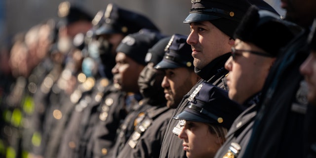 NEW YORK, NY - JANUARY 23: New York City police officers and firemen stand at attention as they await the remains of Police Officer Jason Rivera to be brought to the funeral home on January 23, 2022 in New York City. Rivera and fellow Officer Wilbert Mora were shot Friday night while responding to a domestic violence call between a woman and her adult son. Mora remains hospitalized.