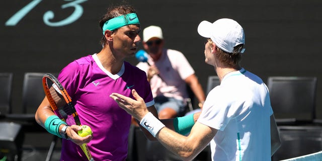 Spain's Rafael Nadal (L) talks to Canada's Denis Shapovalov during their men's singles quarterfinal match on day nine of the Australian Open tennis tournament in Melbourne on Jan. 25, 2022.