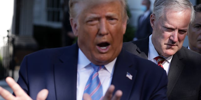 U.S. President Donald Trump speaks as White House Chief of Staff Mark Meadows (R) listens.