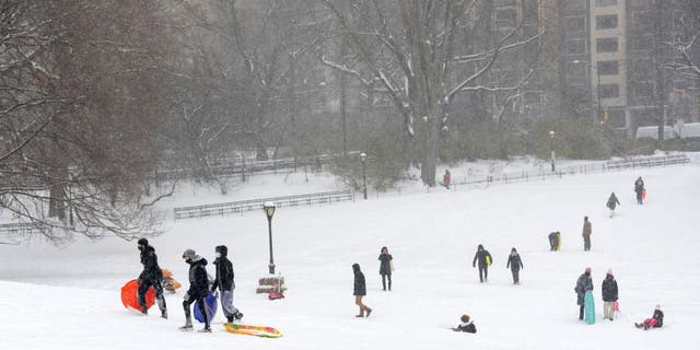 People walk up a mountain used for sledding during a snow storm in Central Park on Feb. 18, 2021, in New York City.