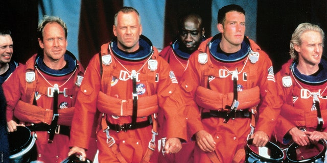 Steve Buscemi, Will Patton, Bruce Willis, Michael Clarke Duncan, Ben Affleck, and Owen Wilson walking in NASA uniforms in a scene from the film "Armageddon," 1998. 