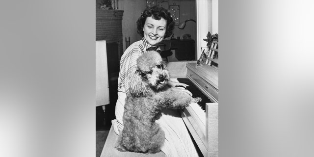A young Betty White with a proud poodle.